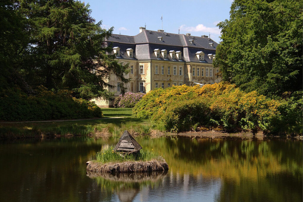 Historisches Schloss in der Oberlausitz mit Parkanlage und Teich – Symbol für regionale Schönheit und Tradition, fotografiert bei Sonnenschein.